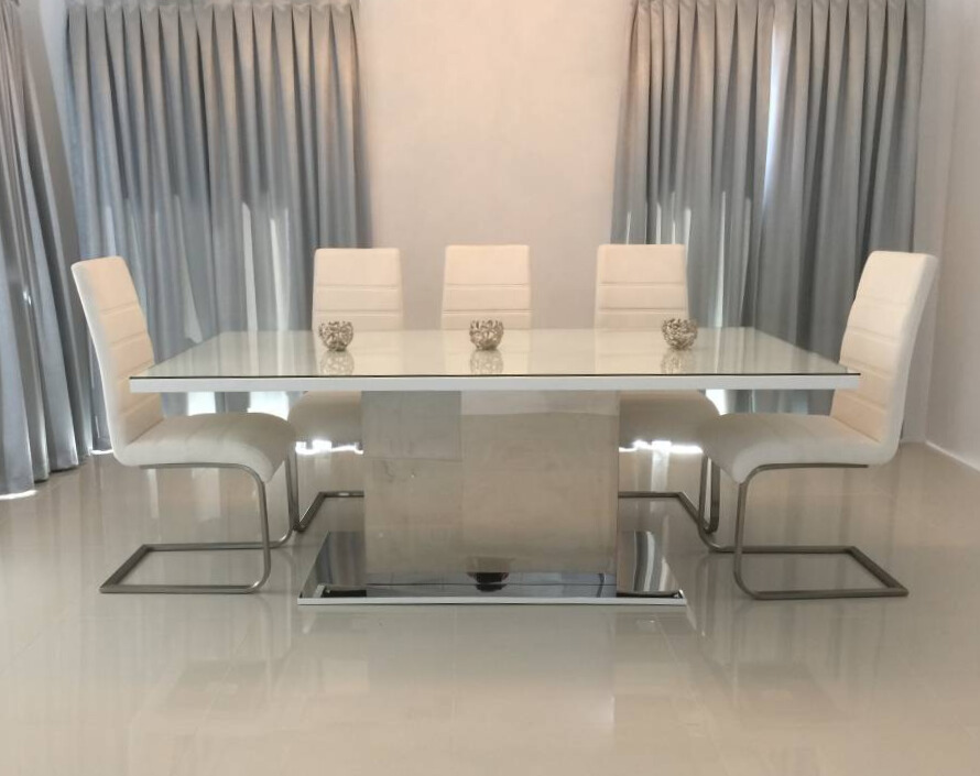 A white dining table with four chairs, creating a stylish and inviting space for meals and gatherings.